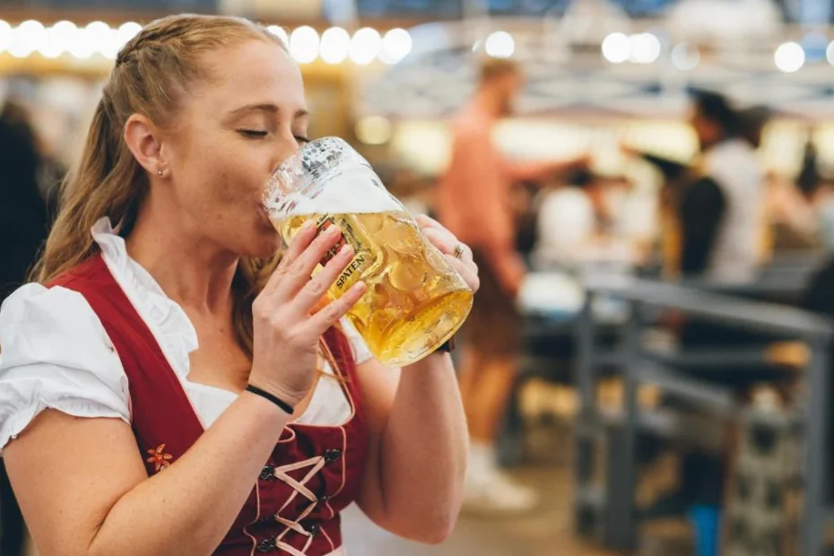 Великі зміни на Oktoberfest 2025: безготівкові платежі, дорожче пиво та нові атракціони – усе, що потрібно знати. На фото: молода дівчина в національму баварському вбранні п'є пиво.