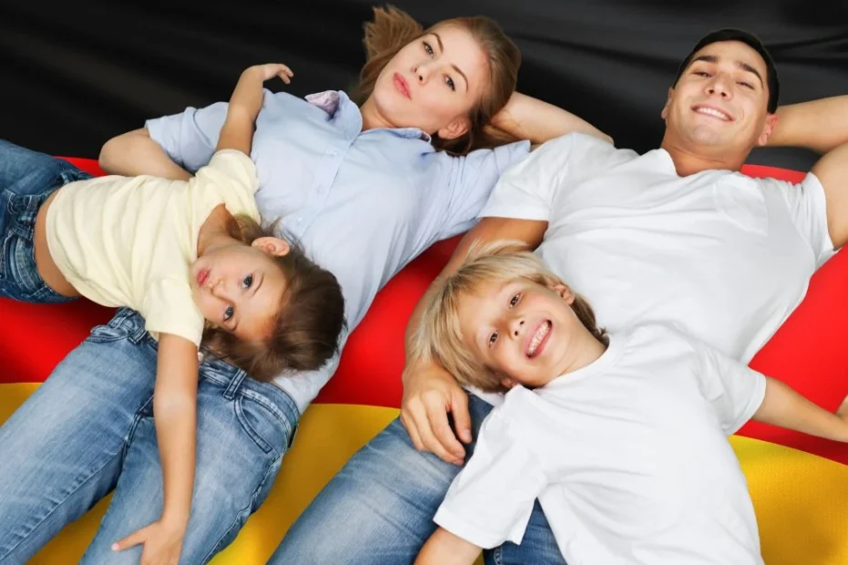 Kindergeld. На фото: молода сім'я з двома дітьми лежить на тлі прапору Німеччини.