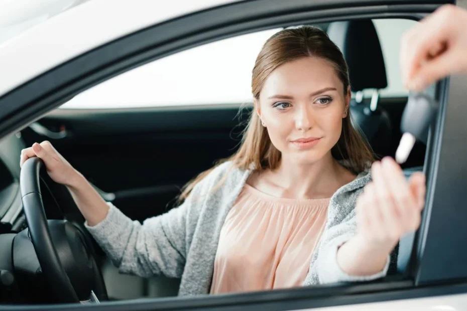водіння чужим автомобілем у Німеччині 2025. На фото: молода жінка сидить за кермом автомобіля і через вікно їй подають ключ від авто.
