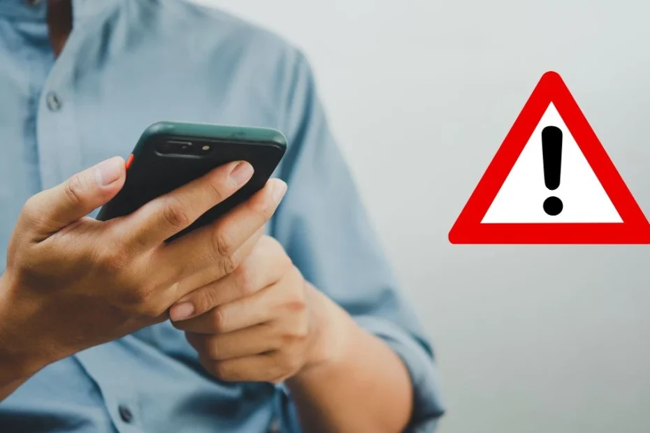 небезпечний додаток на Android. На фото: чоловік тримає в руках смартфон, знак застереження( трикутник зі знаком оклику).