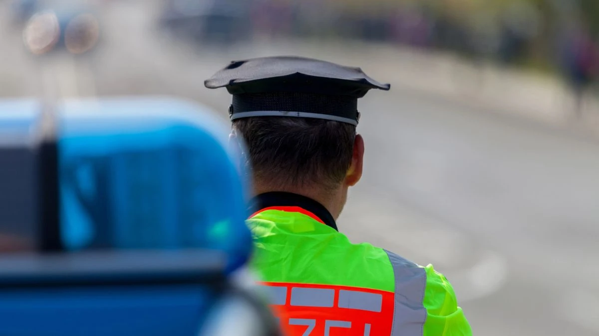 Німеччина попереджає про нову штрафну пастку. На фото: поліцейський стоїть спиною, тло- розмите, на першому плані також розмито поліційний сигнал.