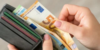 Хто в Німеччині вважається бідним? На фото: гаманець в руках, з якого витягують купюри євро.