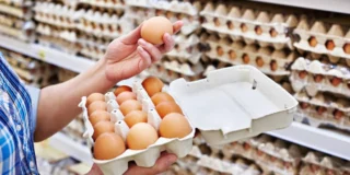 Тривога у німецьких супермаркетах. На фото: на тлі полиць з лотками яєць, відкритий лоток з яйцями в одній руці, а в другій - яйце.
